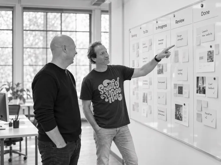 Niels en Hidde bespreken wireframes op de studiomuur